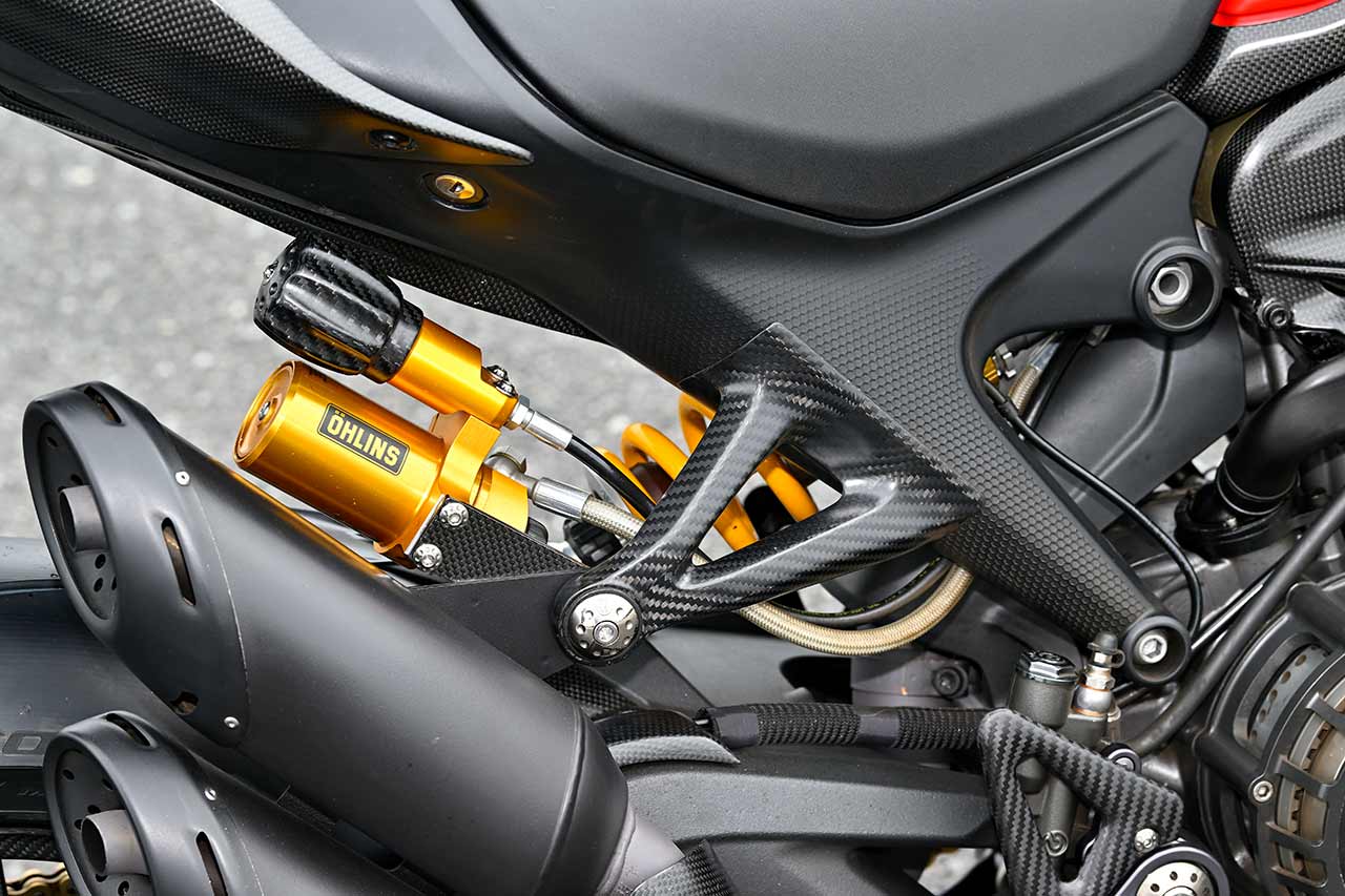 オーリンズ製ショックに換装。モトコルセ製カーボンプリロードアジャスターノブと、ステップセット付属のカーボン製サイレンサーサポートで、軽量化とクリーンな印象に